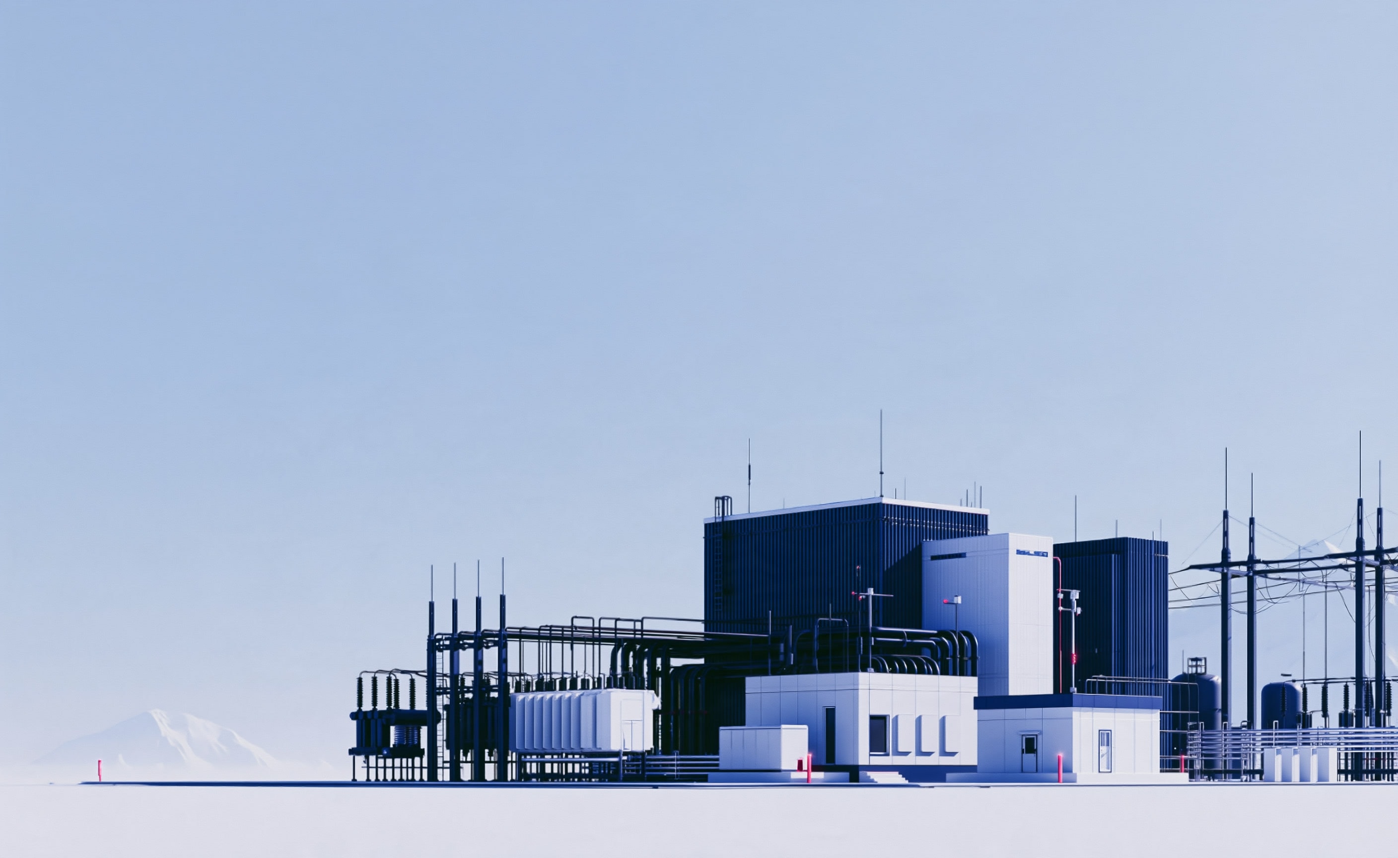 An industrial power facility: switchgear, transformers and overhead lines on a snow-covered plain, mountains in the distance.